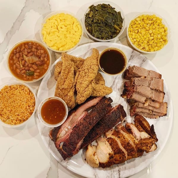 Supreme Barbecue platter with ribs, brisket, chicken, fried fish, baked beans, mac and cheese, collards, corn, and rice.
